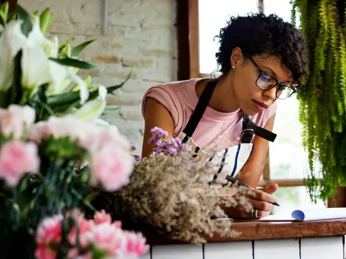 Florist in apron taking notes at the counter, illustrating a hands-on small business featured in a local directory
